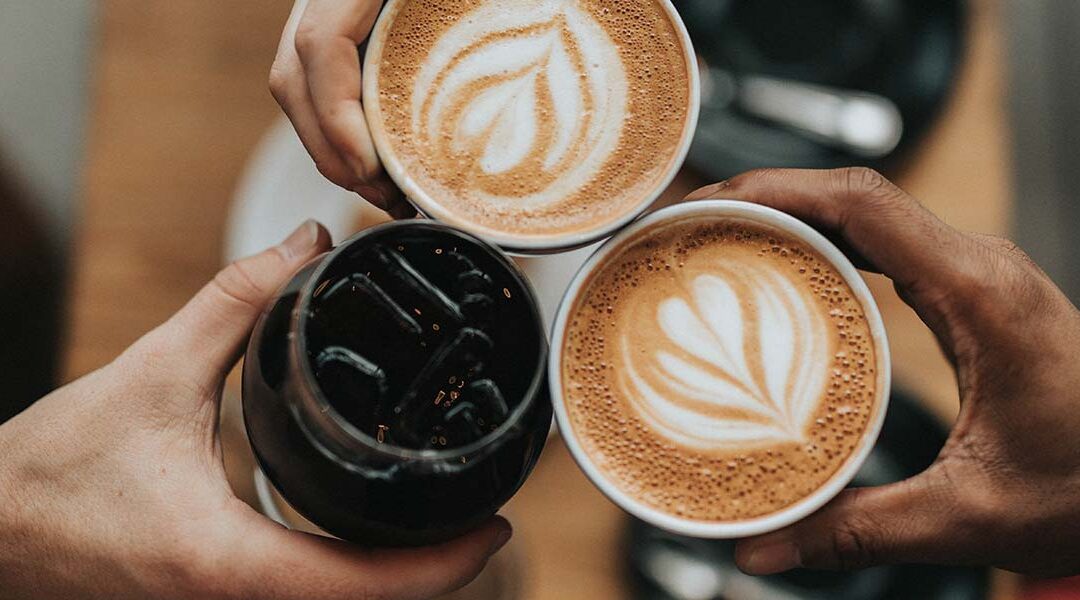 Three lattes with three hands from the top.